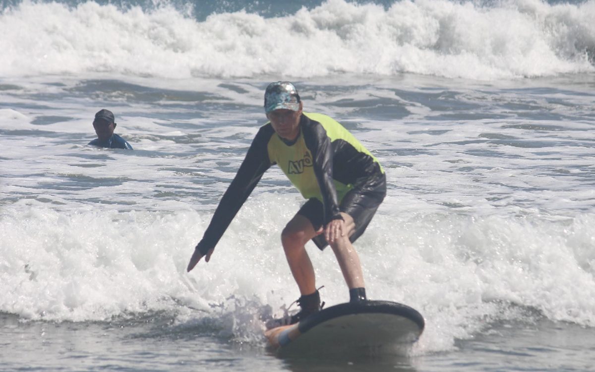 A beginner standing up on a surfboard on Kuta Beach